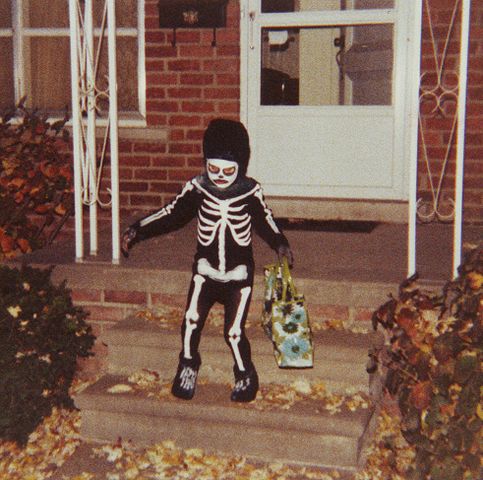 A child trick or treating in a skeleton costume.