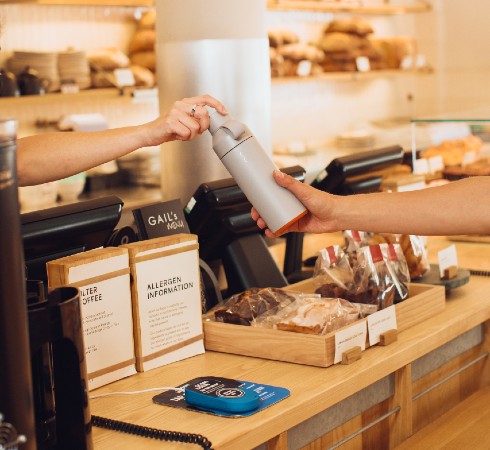 Branded Ocean Bottle being handed over in a cafe